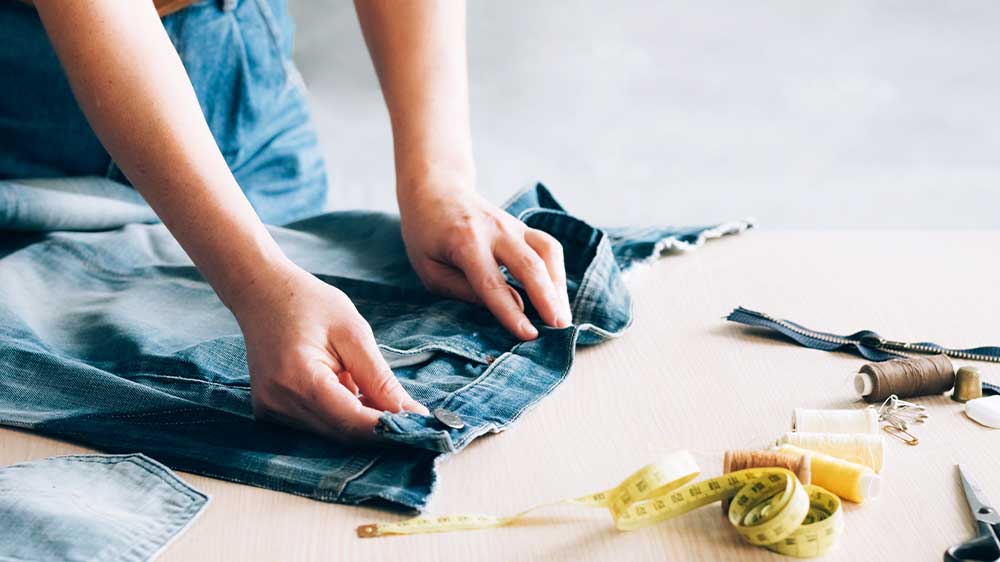 Žena upravuje šířku kalhot a připravuje je na šití_02