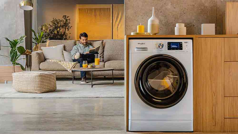 Muž na gauči v pozad&iacute; a stěna s pračkou Whirlpool WPM 87W ADS EE _04