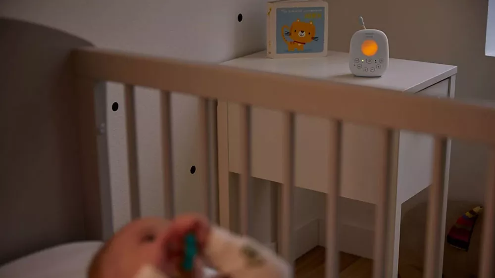 Miminko ležící v postýlce a na nočním stolku položená audio dětská chůvička Philips Avent Advanced SCD 715/52 se zapnutým nočním světlem_04