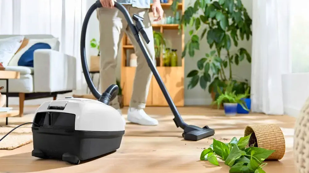 Muž vysává s vysavačem Bosch BGL38WH2 hlínu z převráceného květináče_02