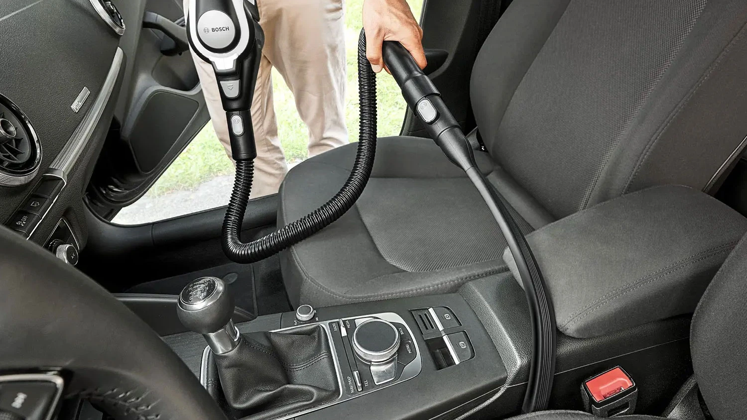 Muž vysává auto pomocí hubice Bosch BHZULFCN