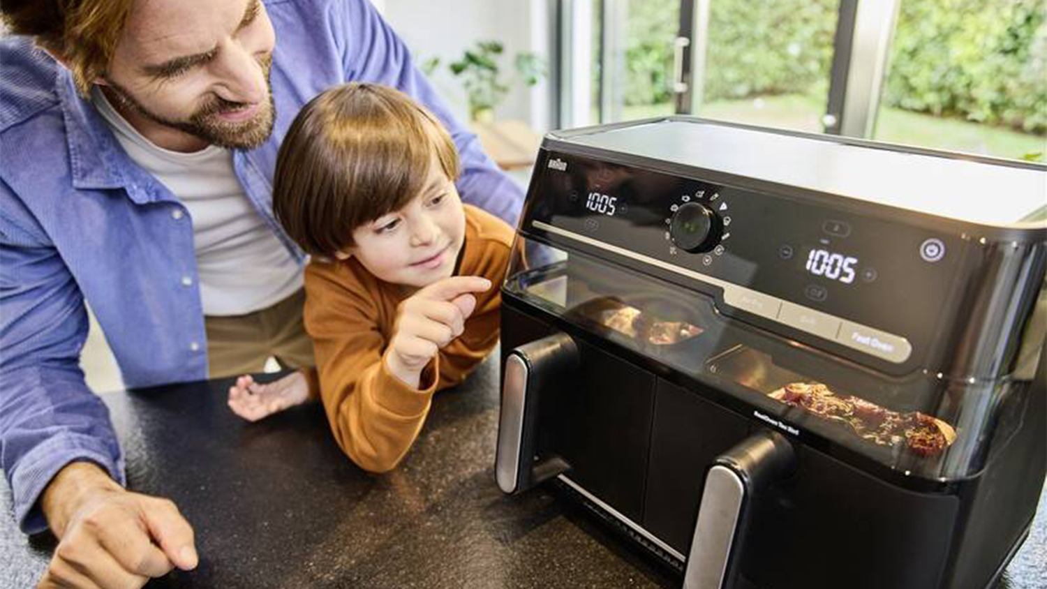 Muž se synem fritují kuřata v horkovzdušné fritéze Braun TwinCook 5 TD5073