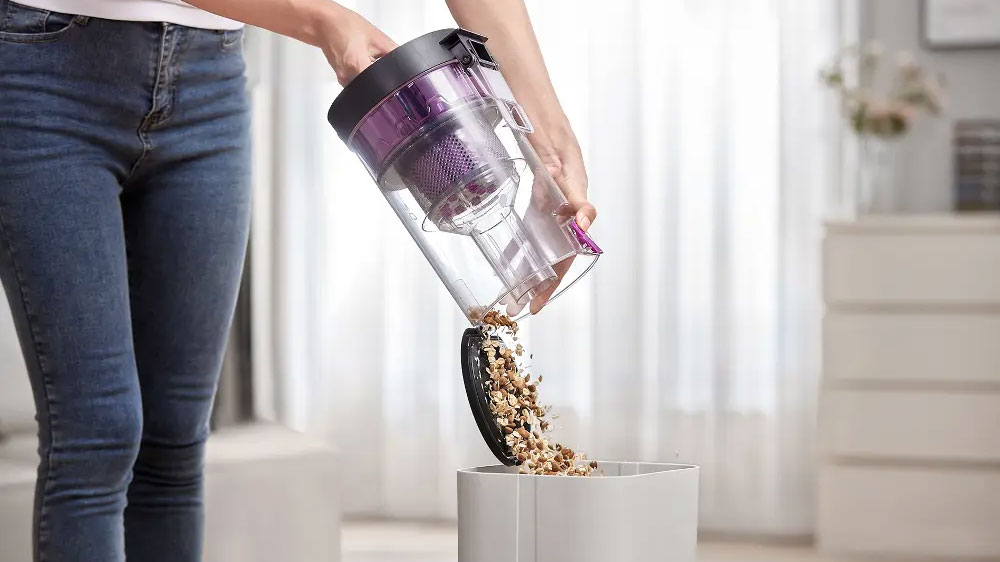 Ženské ruce vysypávající samovypouštěcí stanici robotického vysavače Eureka E10s do odpadkového koše_04