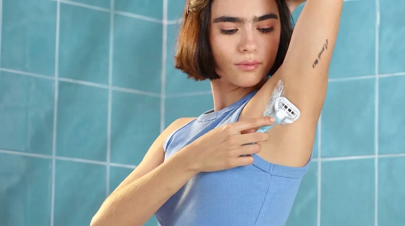 Mladá žena si holí podpazušie dámskym holiacim strojčekom Gillette Venus Extra Smooth.