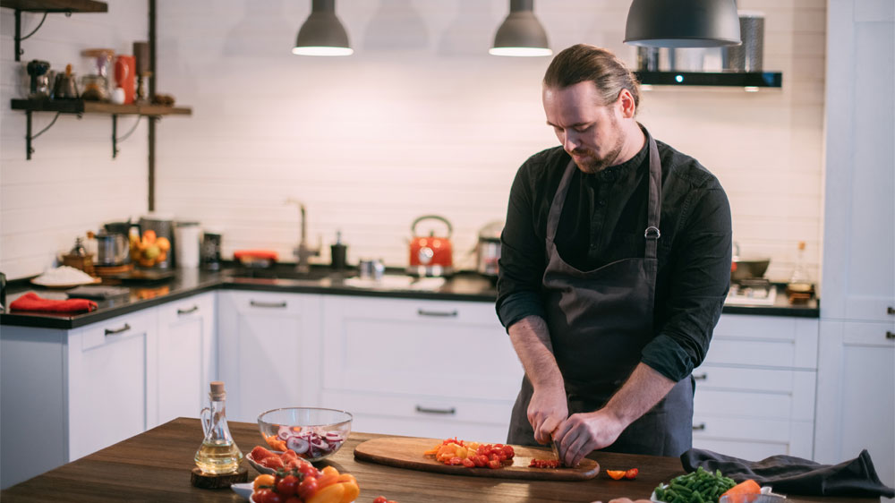 Muž v kuchyni krájí různé druhy zeleniny_02