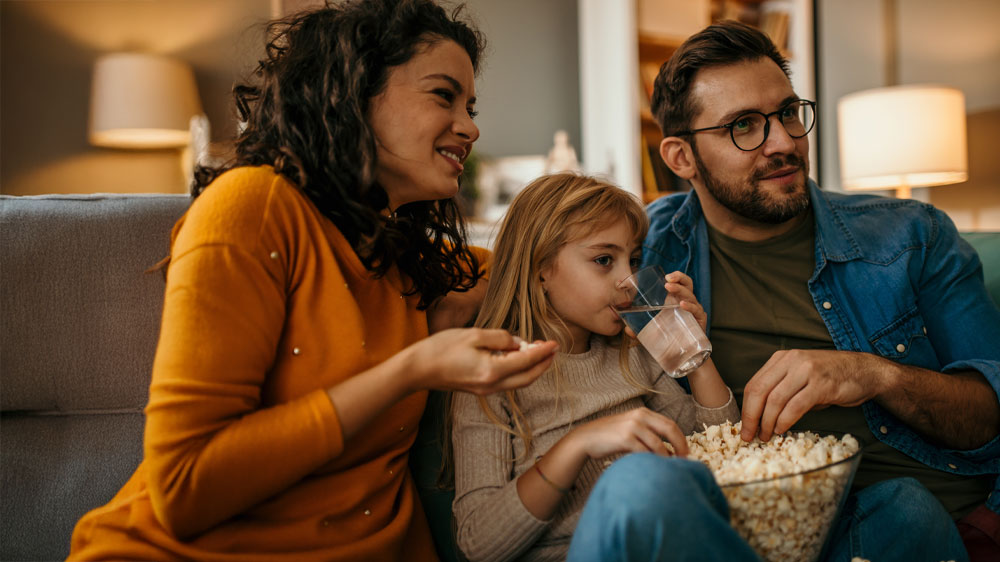 Rodina sedící na pohovce jí popkorn_02