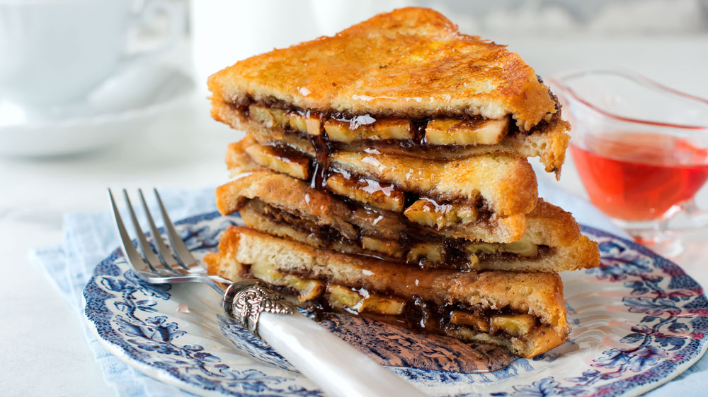 Sendviče plnené čokoládou a banánom naskladané na sebe na tanieri_02