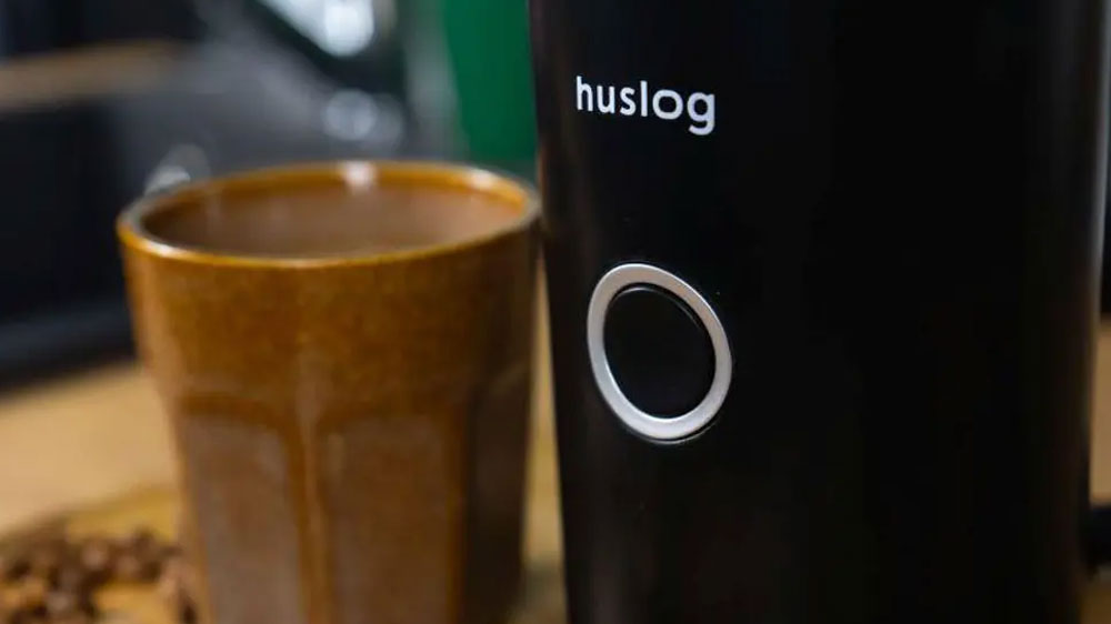 Kávomlýnek Huslog HUS1009 černý na dřevěném prkénku vedle šálku s připravenou kávou_03
