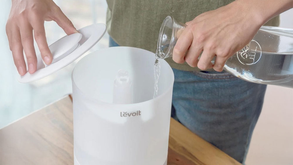 Muž plní nádobu zvlhčovače Levoit Dual 150_03