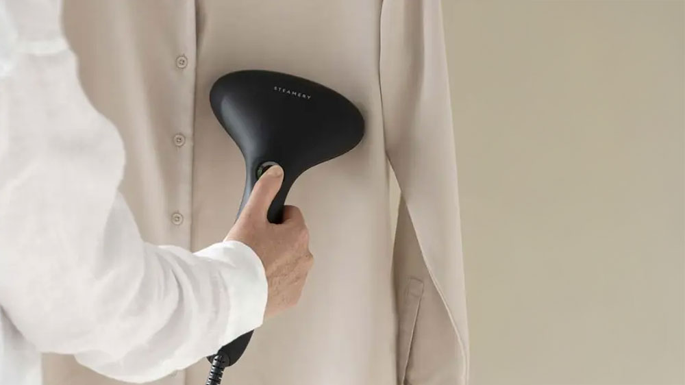 Žena žehlící šaty na ramínku napařovačem_02