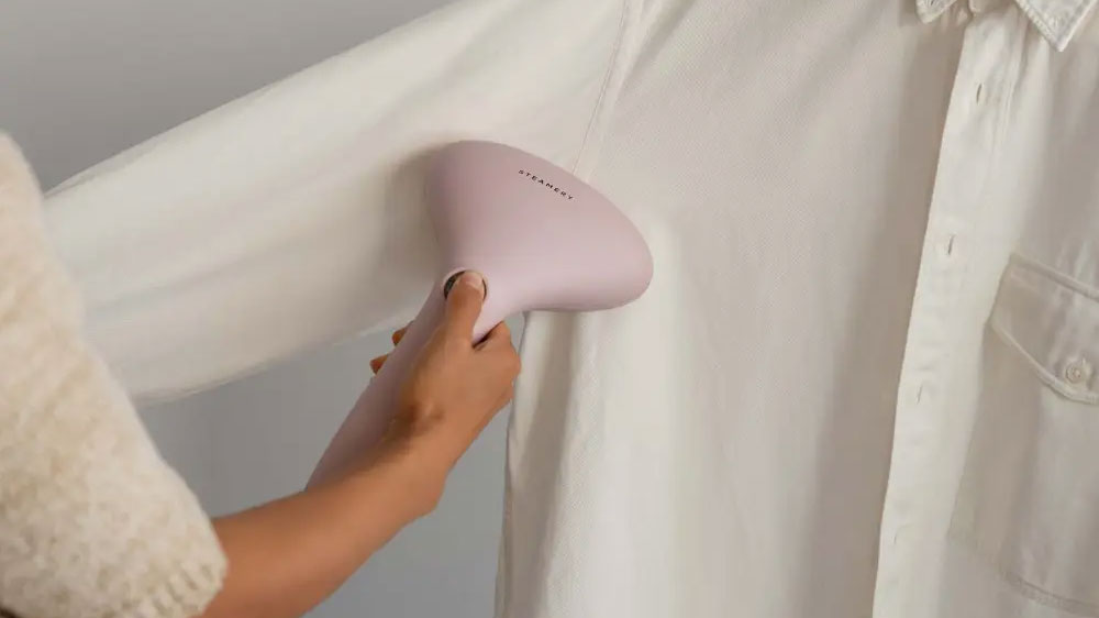 Žena žehlící šaty na ramínku napařovačem_02