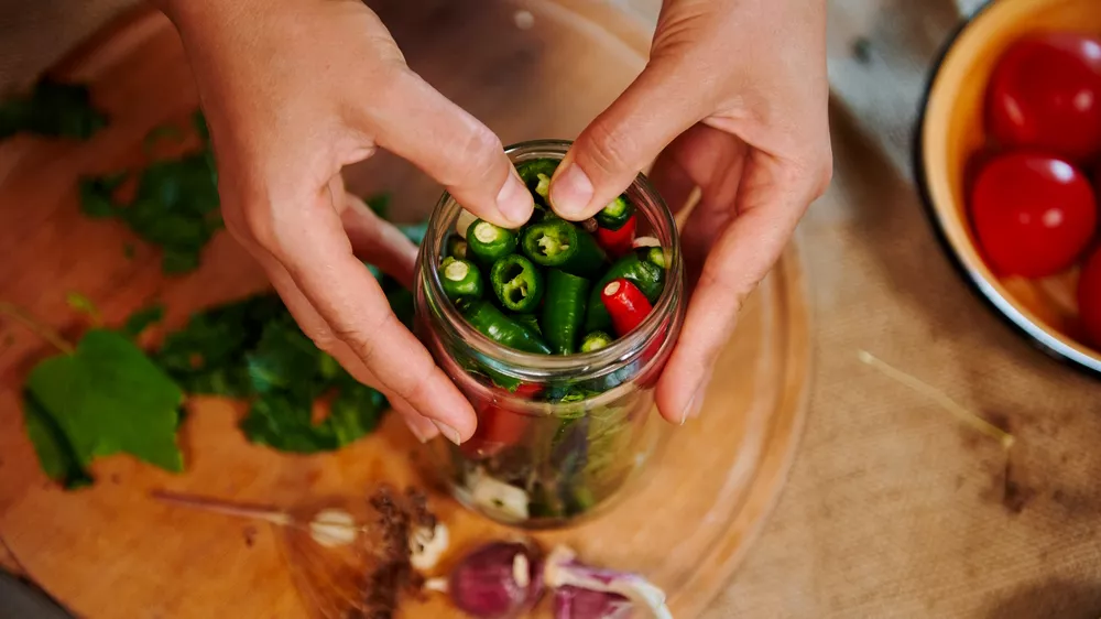 Muž připravuje chilli do zavařovací sklenice_03