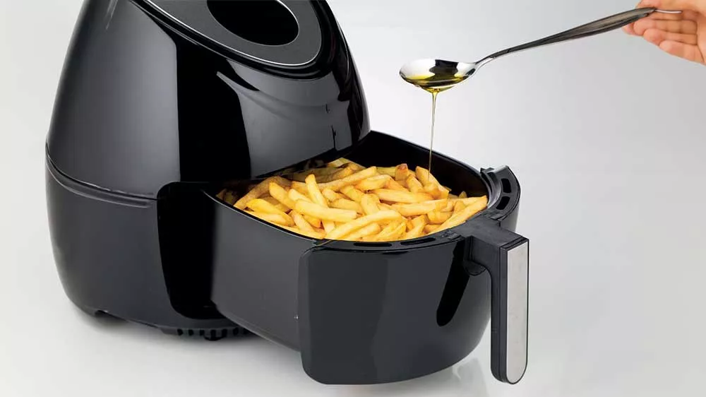 Horkovzdu&scaron;n&aacute; frit&eacute;za Ariete 4618 naplněn&aacute; hranolkami pol&eacute;van&yacute;mi lžičkou oleje_02
