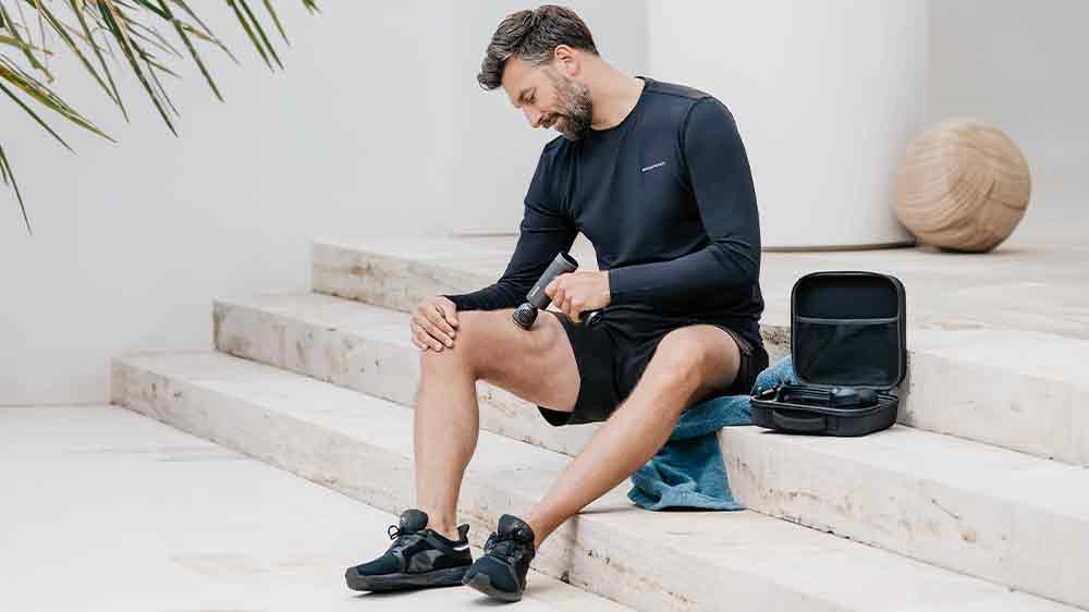 Muž si masíruje stehno s masážní pistolí Beurer MG 195_02