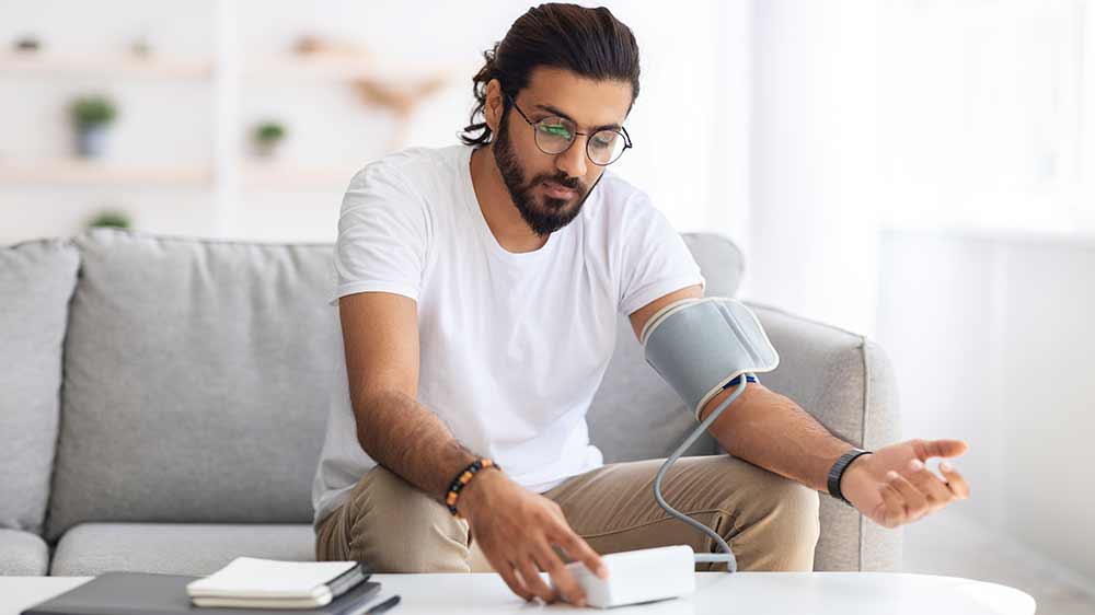 Mladý muž si měří tlak s pažním tlakoměrem_02