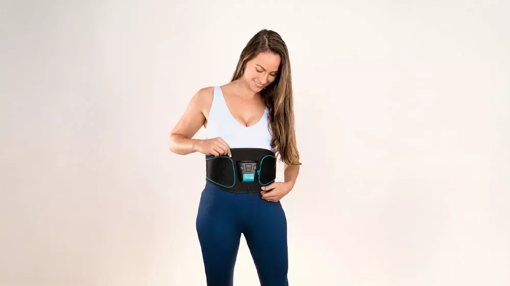 Muž sedí na stoličke pri počítači a má nasadený elektrostimulátor Beurer Corefit I_02
