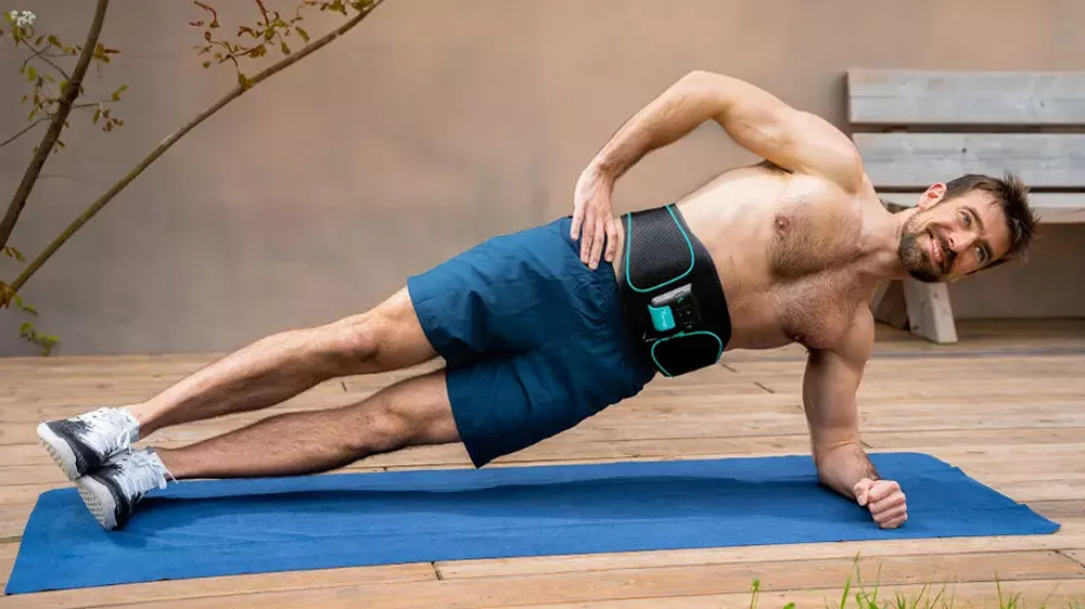 Usmievajúca sa žena sedí na lúke a má nasadený elektrostimulátor Beurer Corefit I_03