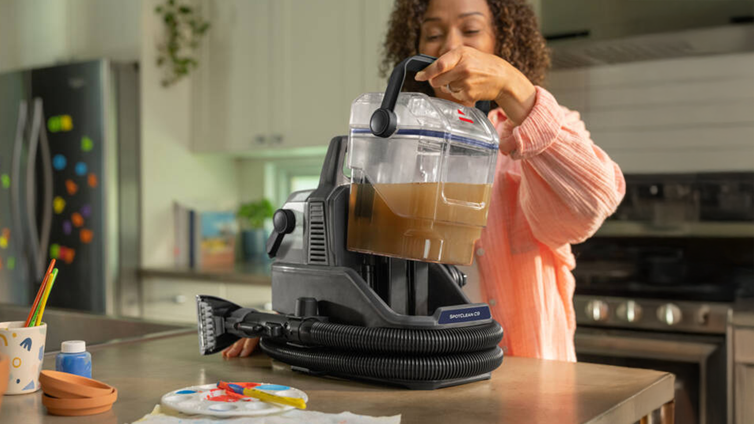 Žena vyber&aacute; n&aacute;drž na &scaron;pinav&uacute; vodu tepovača kobercov Bissell 3989N SpotClean C9 Select