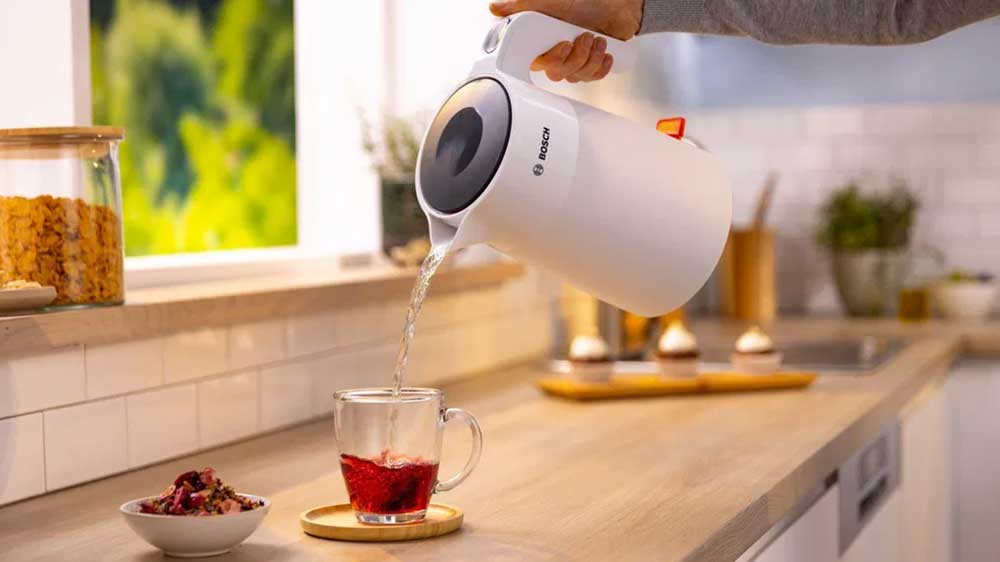 Ruka zalévající šálek s čajem vodou z rychlovarné konvice Bosch TWK2M161 MyMoment_02