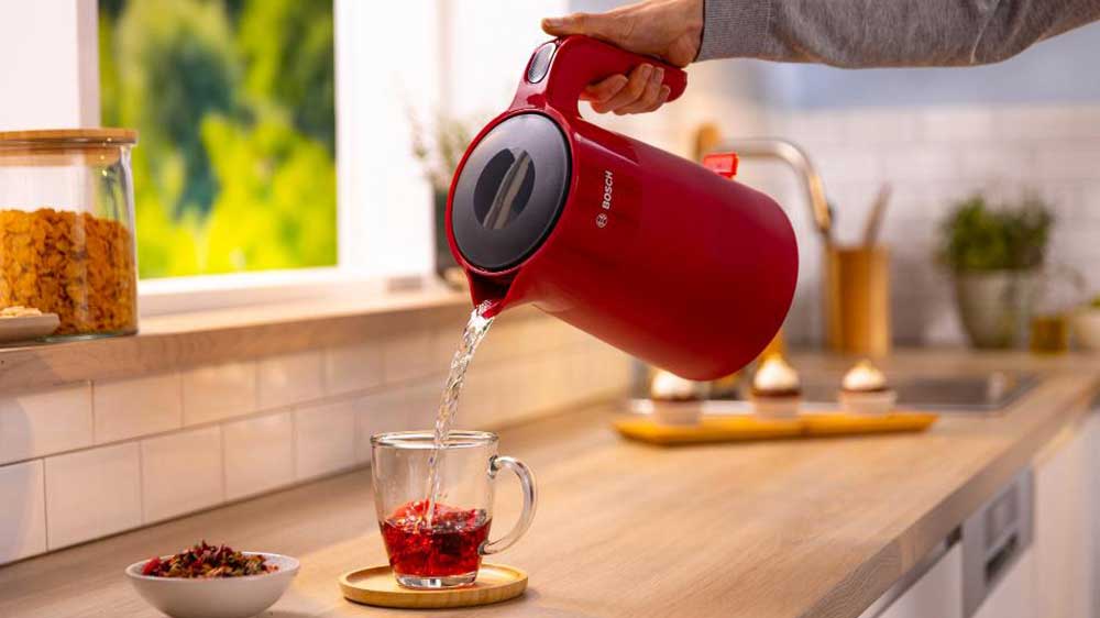 Ruka zalévající šálek s čajem vodou z rychlovarné konvice Bosch TWK2M164 MyMoment_02