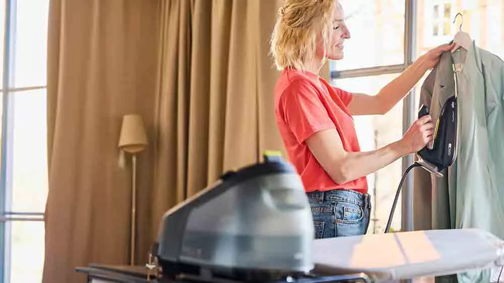 Žena žehlí pomocí parního generátoru Braun CareStyle 3 IS3257 BK vertikálně košili