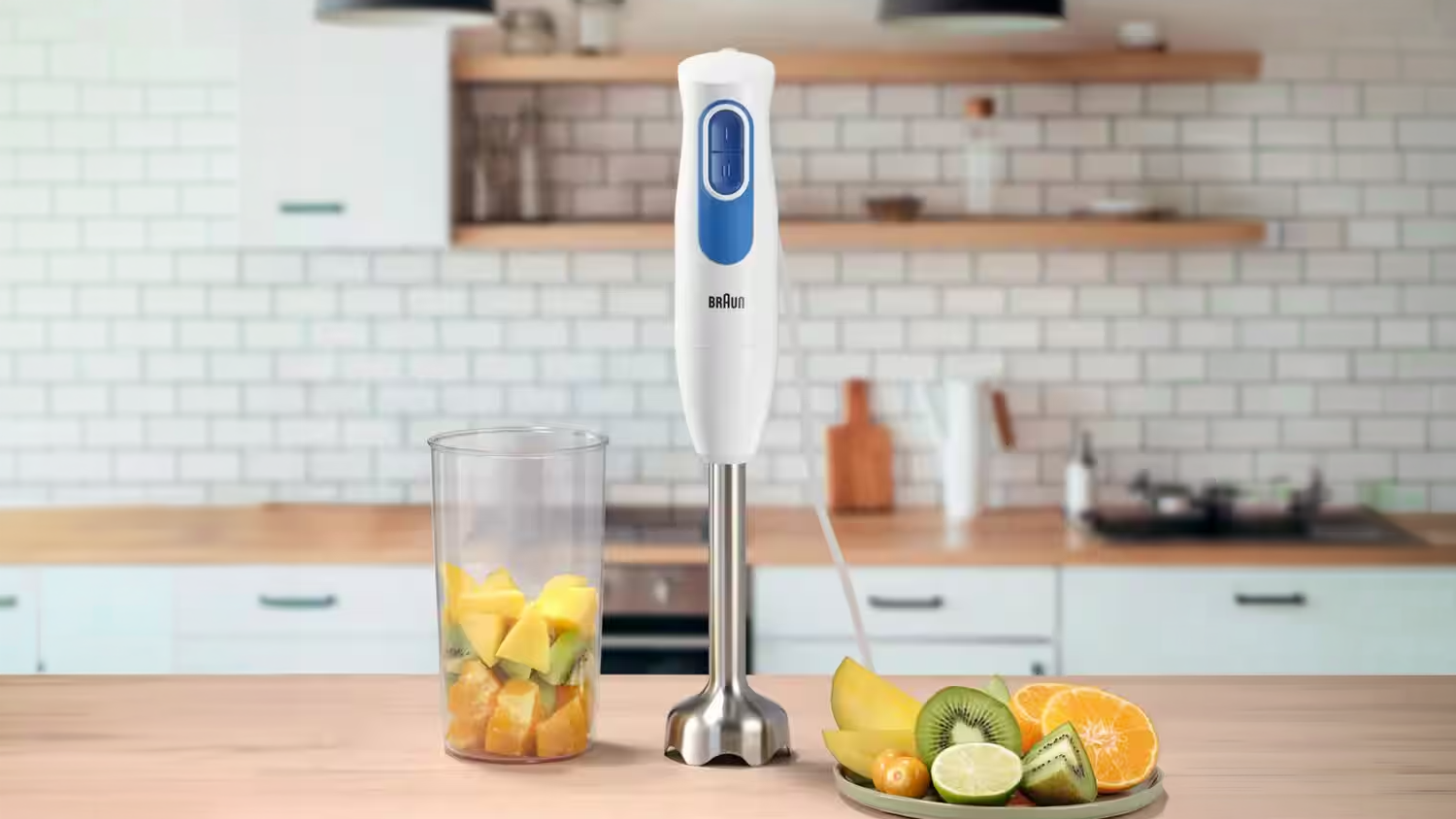 Tyčový mixér Braun MultiQuick 2 MQ20001MWH na stole vedle doměrky a talíře s ovocem