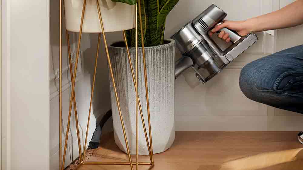 Úklid s ruční jednotkou tyčového vysavače Dreame R20 za květináčem_03