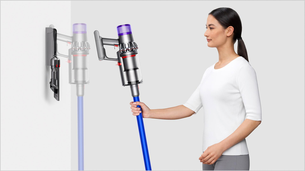 Mladá žena umisťuje tyčový vysavač Dyson V11 Advanced pomocí držáku na zeď_02