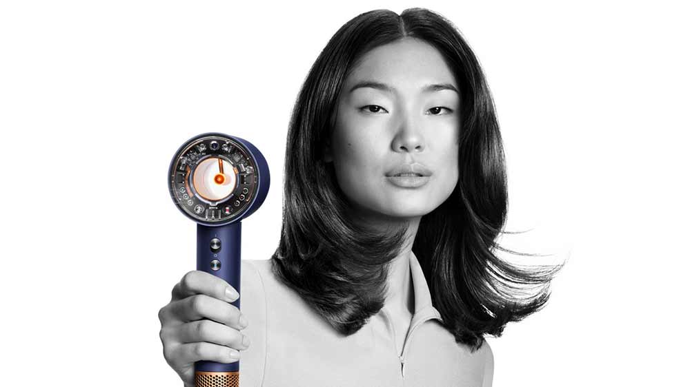 Žena drží sušič vlasov Dyson Supersonic HD07 T3/T4 pruská modrá/medená_02