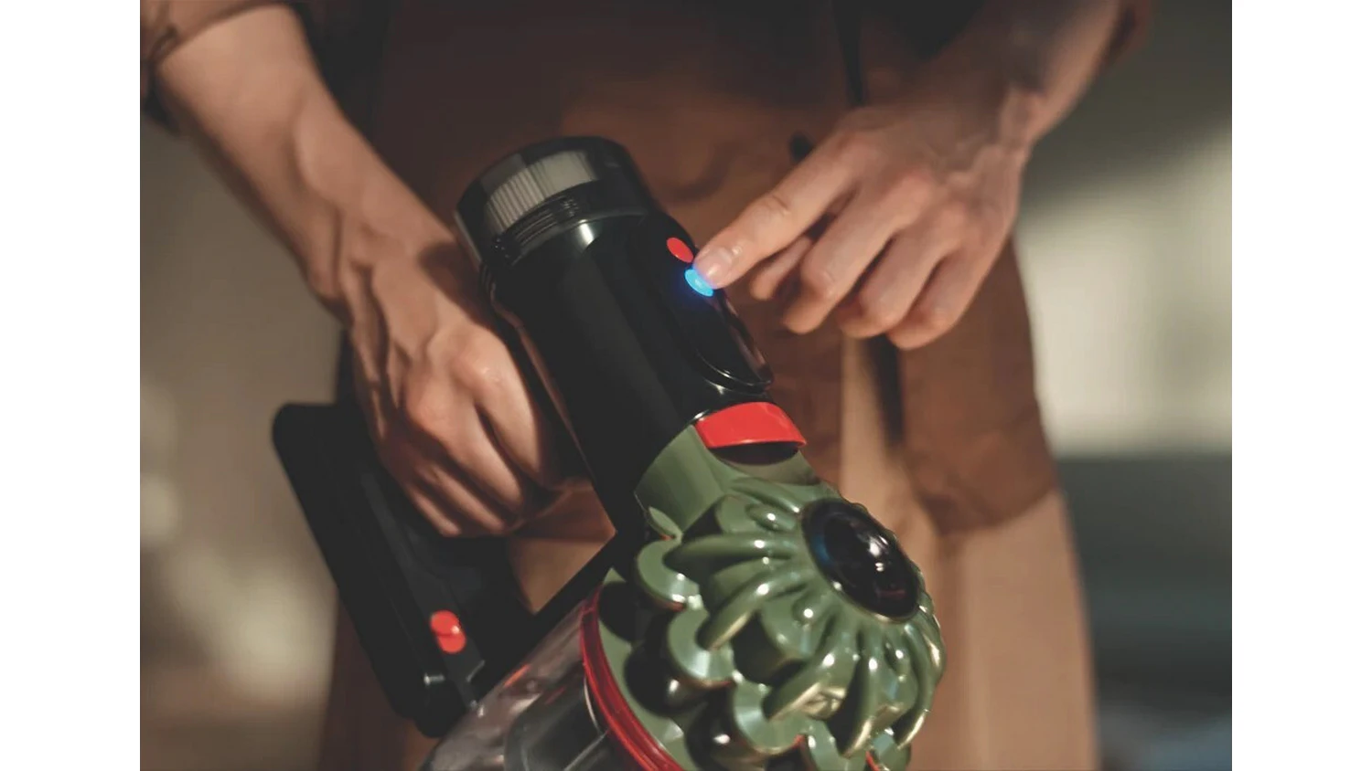 Muž mačk&aacute; ovl&aacute;dac&iacute; tlač&iacute;tko na vysavači Dyson V8 Cyclone