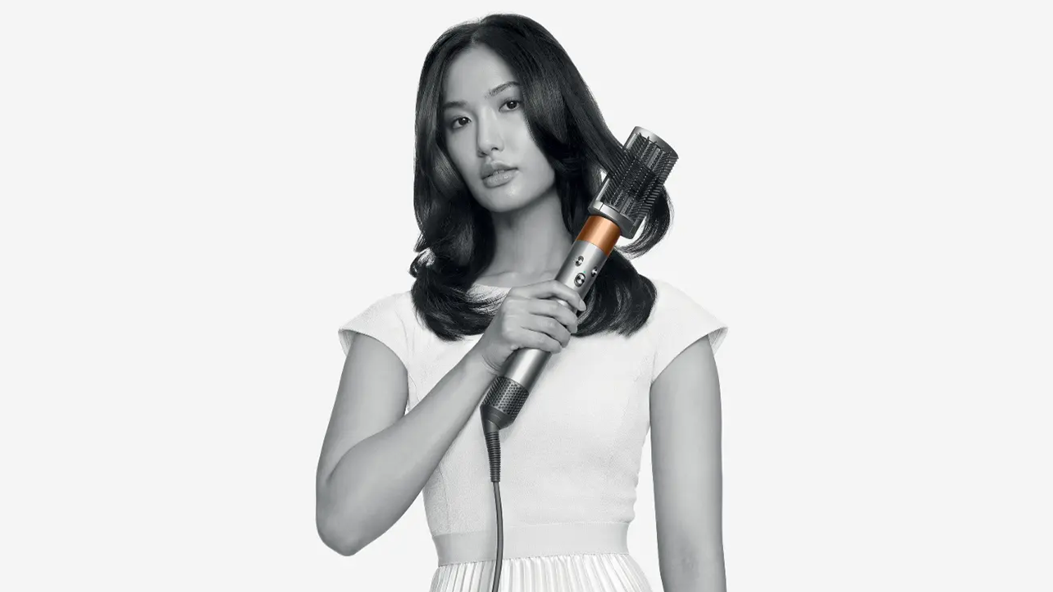 Žena si prečesáva vlasy slučkovou kefou na multistyleri Dyson