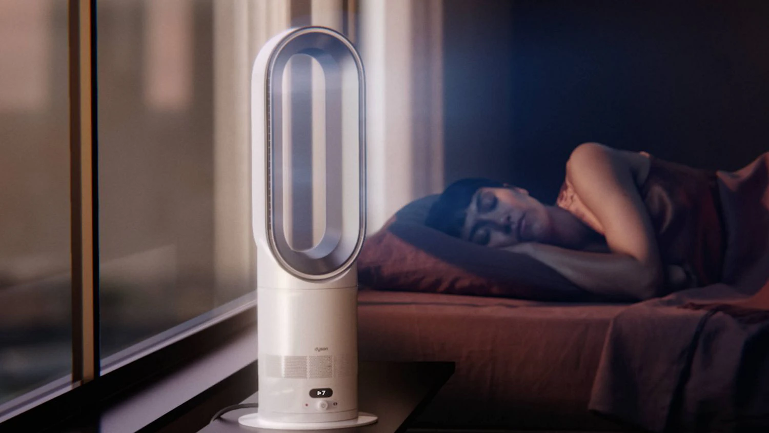 Žena spiaca na posteli a stole s ventil&aacute;torom Dyson