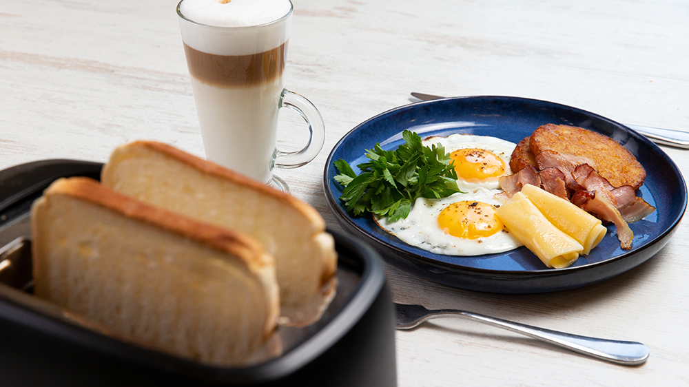 Chléb v topinkovači, káva a vejce se slaninou a sýrem na talíři_02