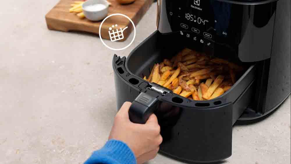Člověk vytahuj&iacute;c&iacute; n&aacute;dobu s hranolkami z horkovzdu&scaron;n&eacute; frit&eacute;zy Electrolux EAF7B_03