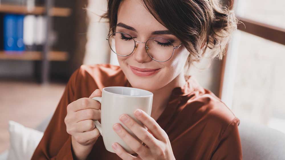 Žena držící hrnek s kávou v obou rukách vychutnávající jeho aroma_02