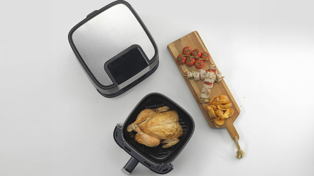 Horkovzdušná fritéza Gorenje AF1350DWB z vrchu s vytaženým košem, ve kterém je pečené kuře_03