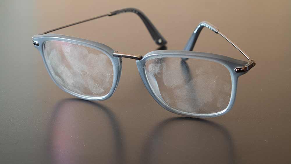 Dioptrické brýle ležící na desce se spoustou otisků prstů na sklíčkách_3