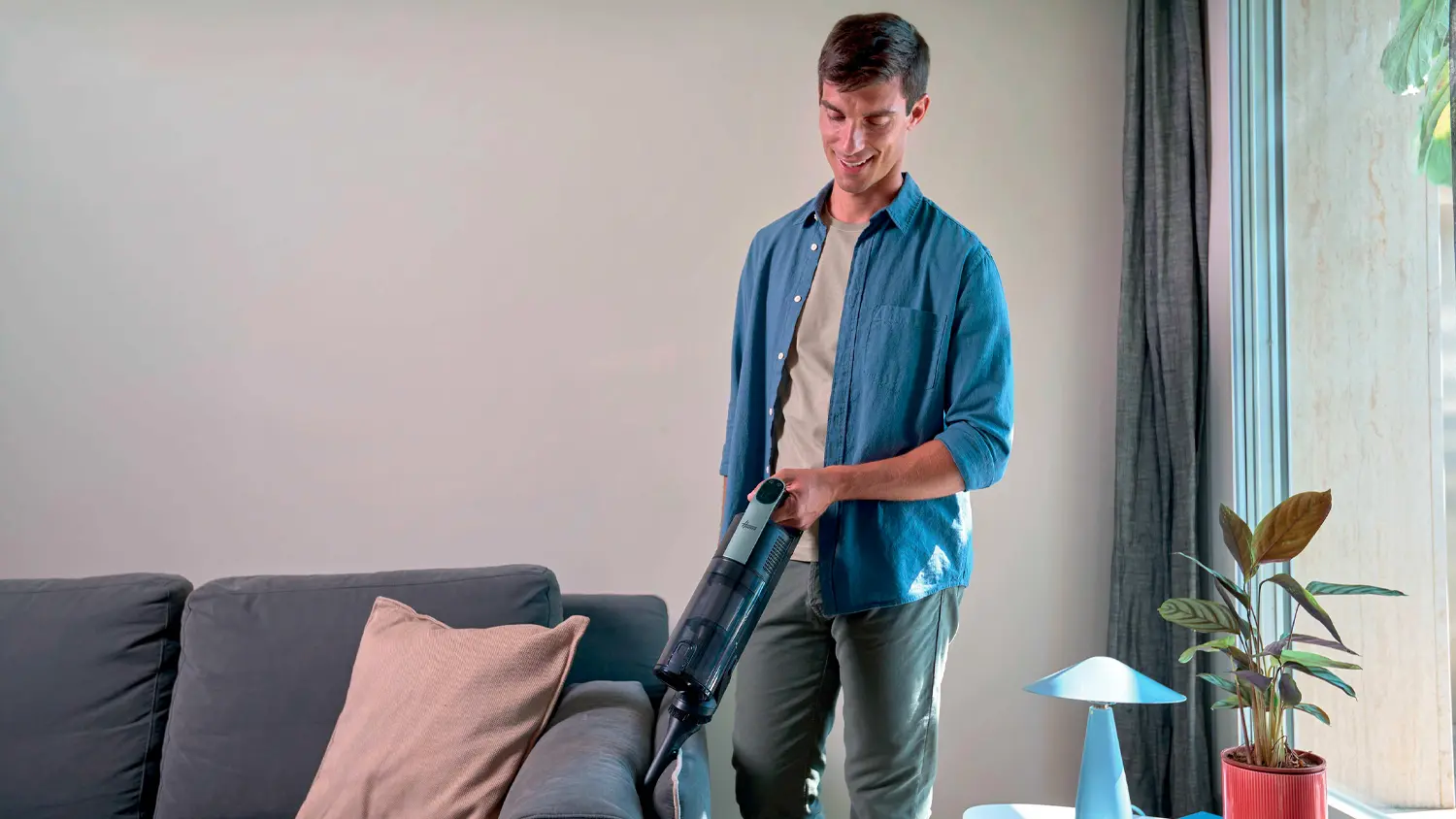 Muž vysáva ručnou jednotkou vysávača Hoover HF310H 011