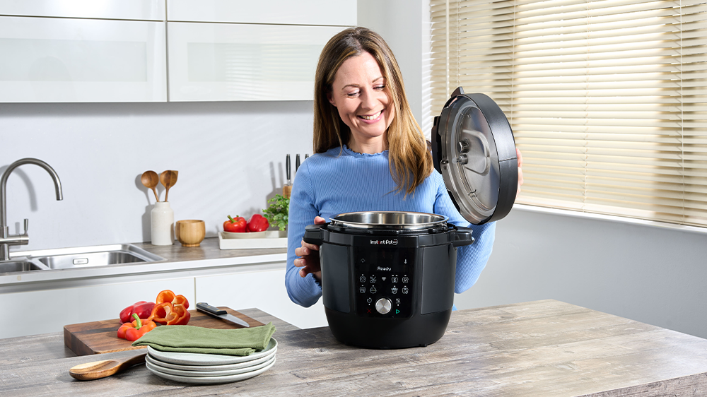 Žena se usmívá a otevírá multifunkční hrnec Instant Pot Plus