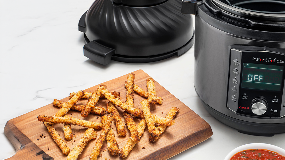 Multifunkčný hrniec Instant Pot Pro Crisp zobrazený s cestovinami so syrom na tanieroch