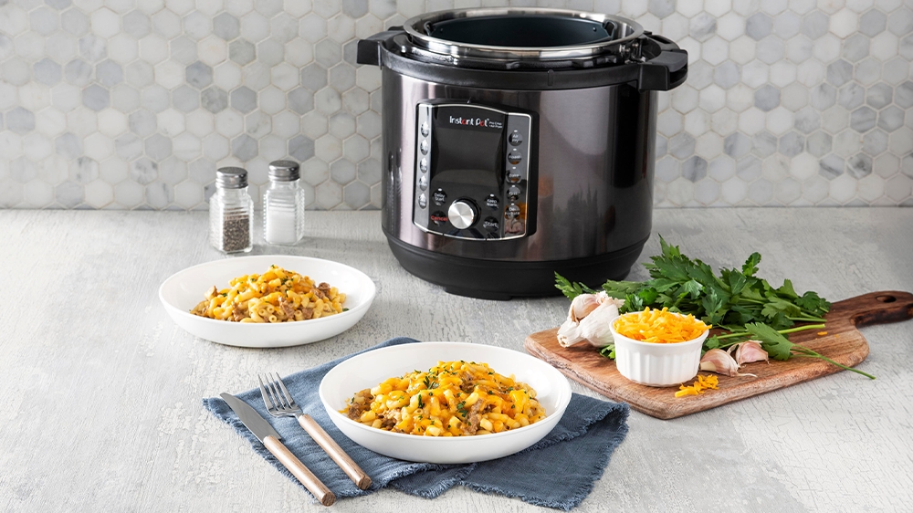 Multifunkční hrnec Instant Pot Pro Crisp vyobrazený s těstovinami se sýrem v talířích