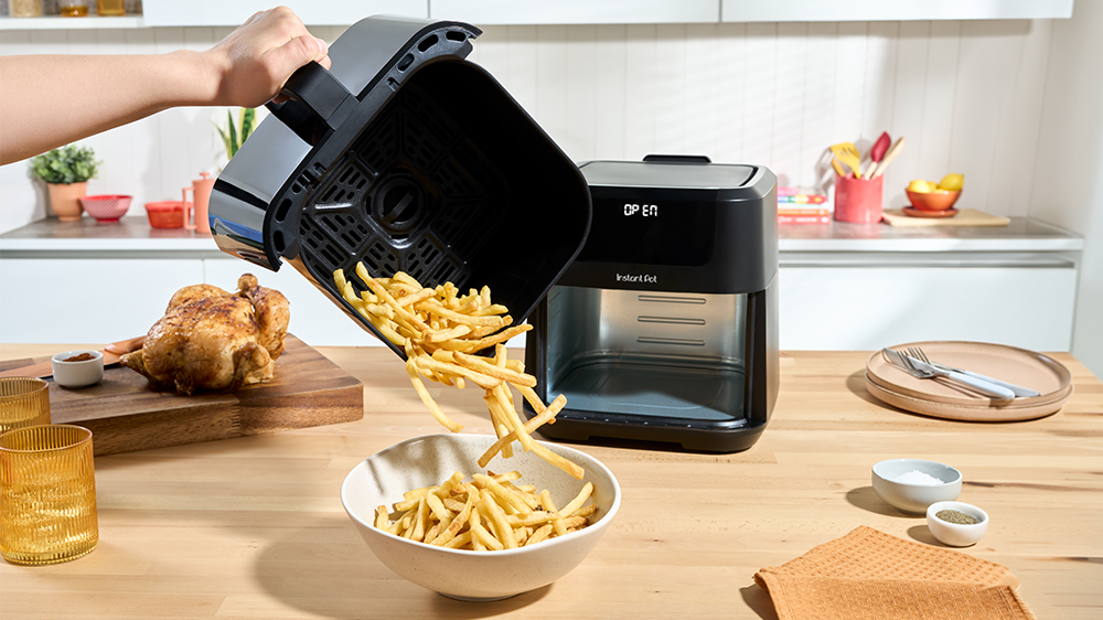 Osoba sype čerstvě fritované hranolky z horkovzdušné fritézy