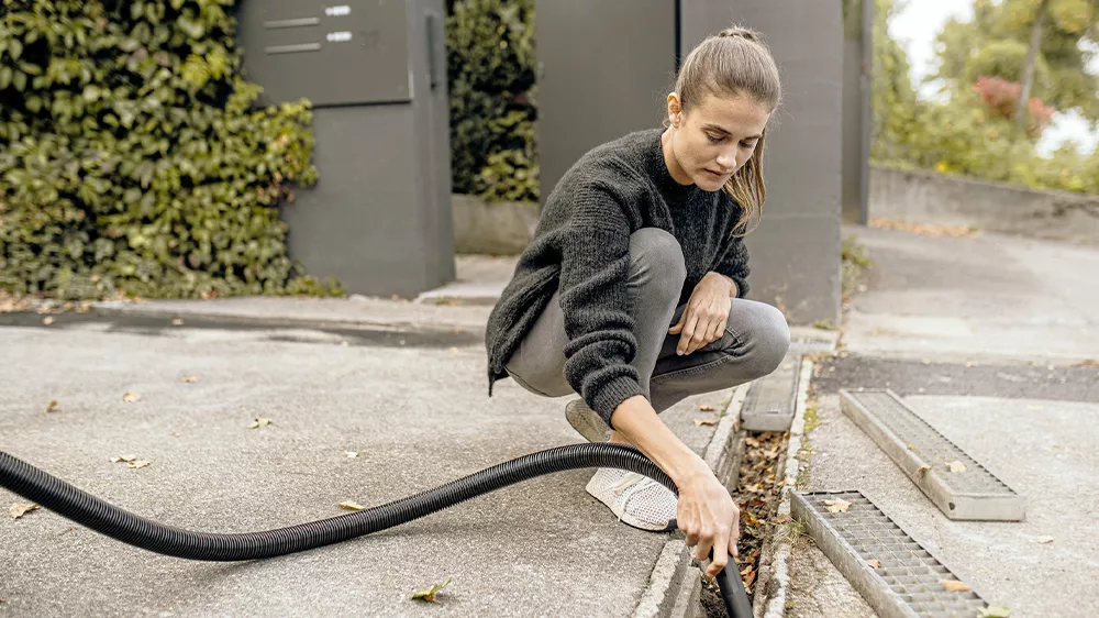 Žena vysává listí ze žlabu_02