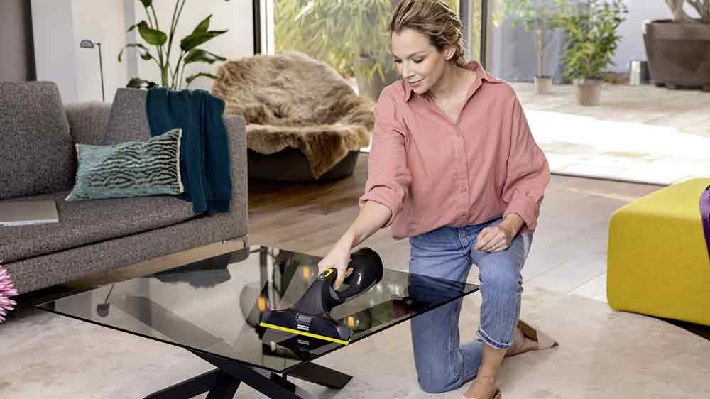 Žena čist&iacute;c&iacute; skleněn&yacute; stolek v ob&yacute;v&aacute;ku vysavačem na okna K&auml;rcher WV 5 Plus Anniversary Edition_03