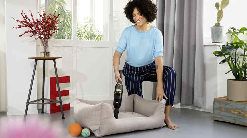 Žena vysávající psí pelíšek ručním vysavačem KÄRCHER CVH Anniversary Edition_02