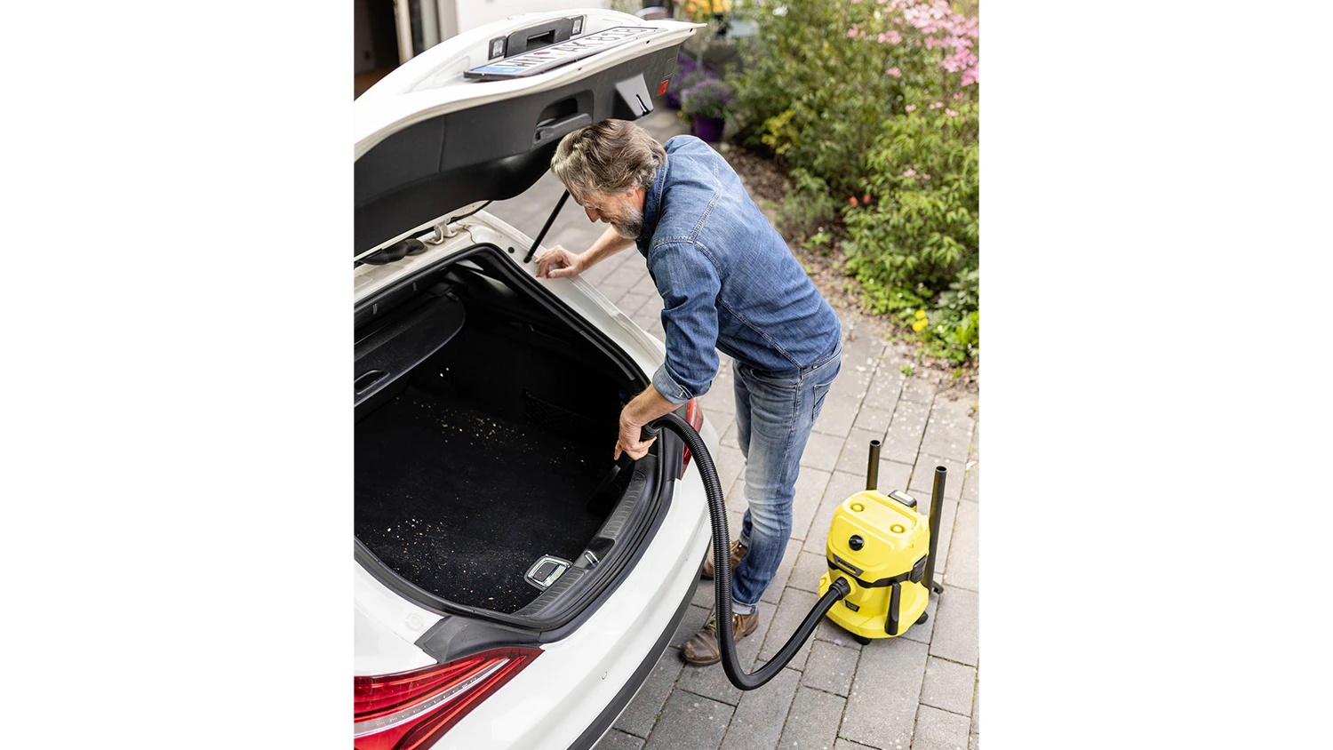 Muž ukl&iacute;z&iacute; auto pomoc&iacute; vysavače Karcher WD 2-18 V-12/18