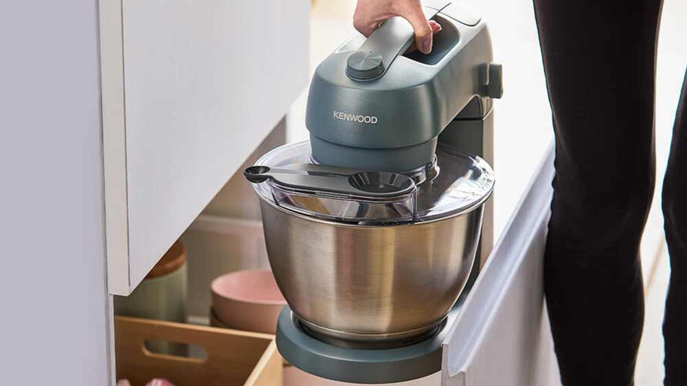 Žena vyndává kuchyňského robota Kenwood KZM35.000GY ze zásuvky v kuchyni_02