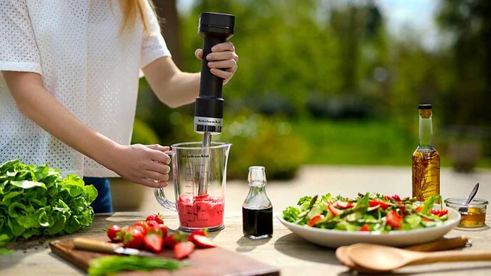 Žena používající bezdrátový tyčový mixér KitchenAid 5KHBRV00BM_03