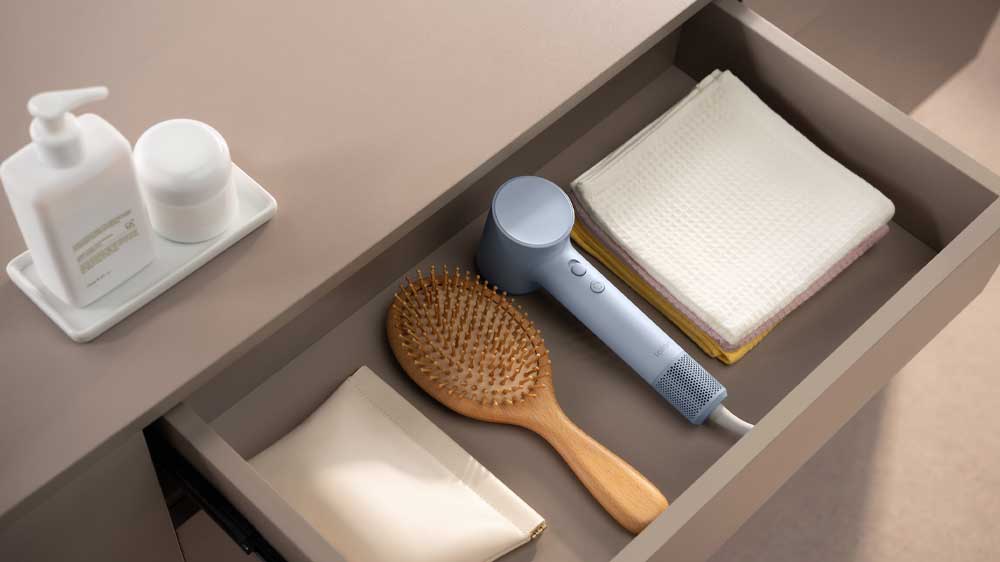 Fén uložený v šuplíku komody mezi hřebenem a ručníkem_03