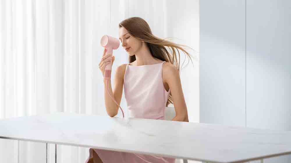 Žena sedící za stolem používá fén Laifen SE 2 Special Pink_02